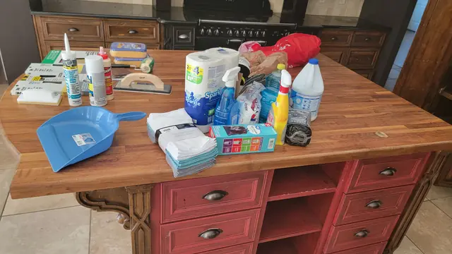 Cleaning and surface-prep supplies organized on a butcher-block kitchen island