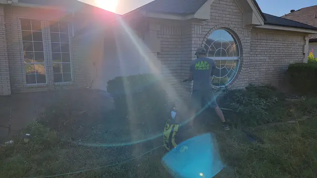 A technician pressure washing the brick exterior of a home