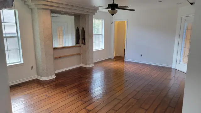 A completed living room remodel with refinished hardwood floors and freshly painted walls