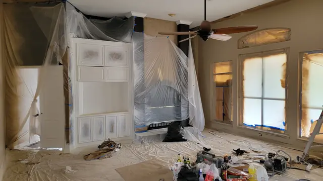 A freshly painted white built-in entertainment center with fireplace and windows masked in plastic