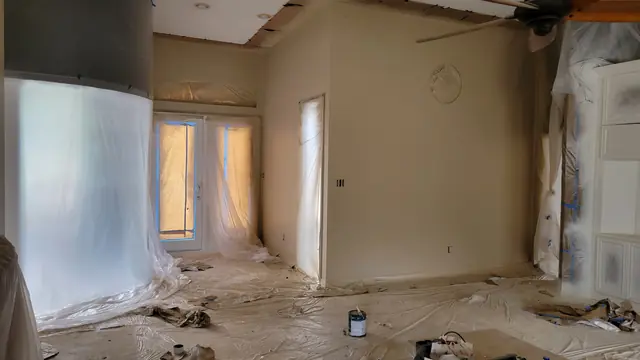 A room with freshly painted beige walls and doors and windows protected with masking paper