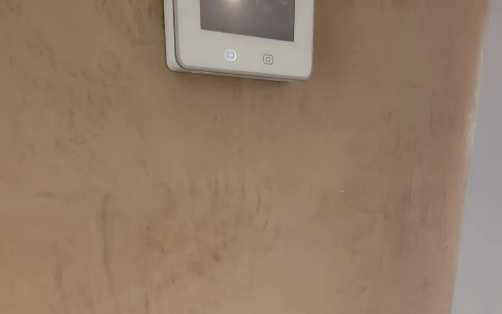 A wall-mounted thermostat above a freshly patched and prepped wall